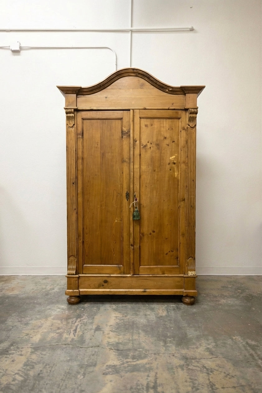 Antique pine armoire with arched bonnet top, carved columns and bun feet